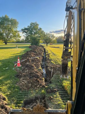 A utility trench dug alongside a grass field at golden hour